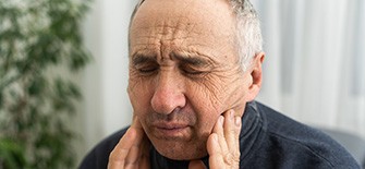 Patient in Indianapolis rubbing his cheeks without dentures